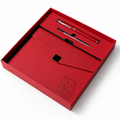 A red gift set presented in an open red box on a white background, containing a red pen and a matching red envelope or card holder with a small embossed gift box logo.